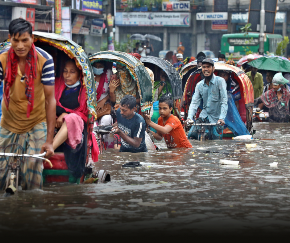 A flooded street, people are wading through the water