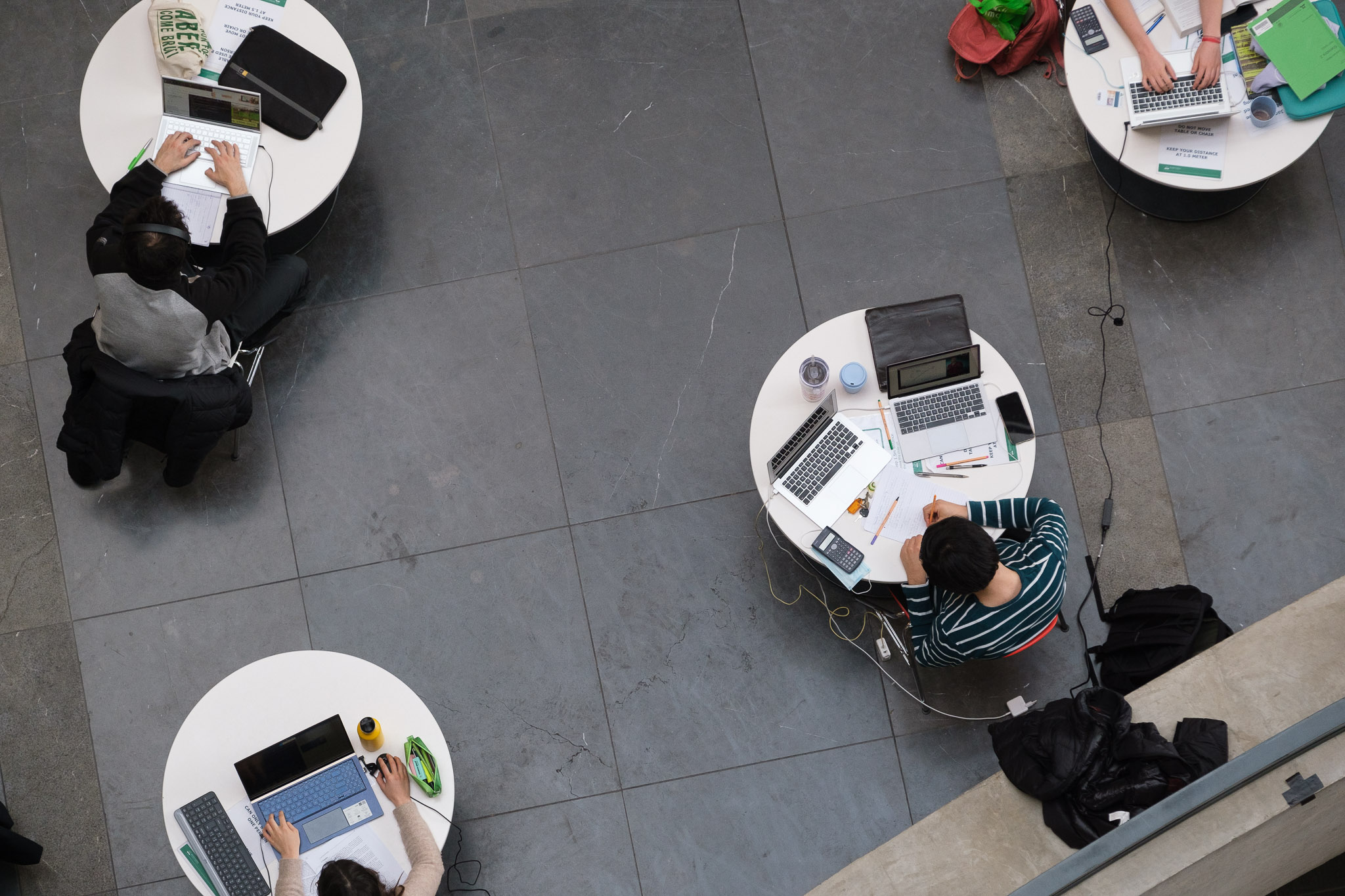 Studenten in het Forumgebouw, één per tafeltje