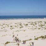 Studenten lopen door de duinen naar de zee