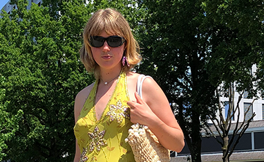 Imme wearing a yellow dress, open black shoes and a ratan bag