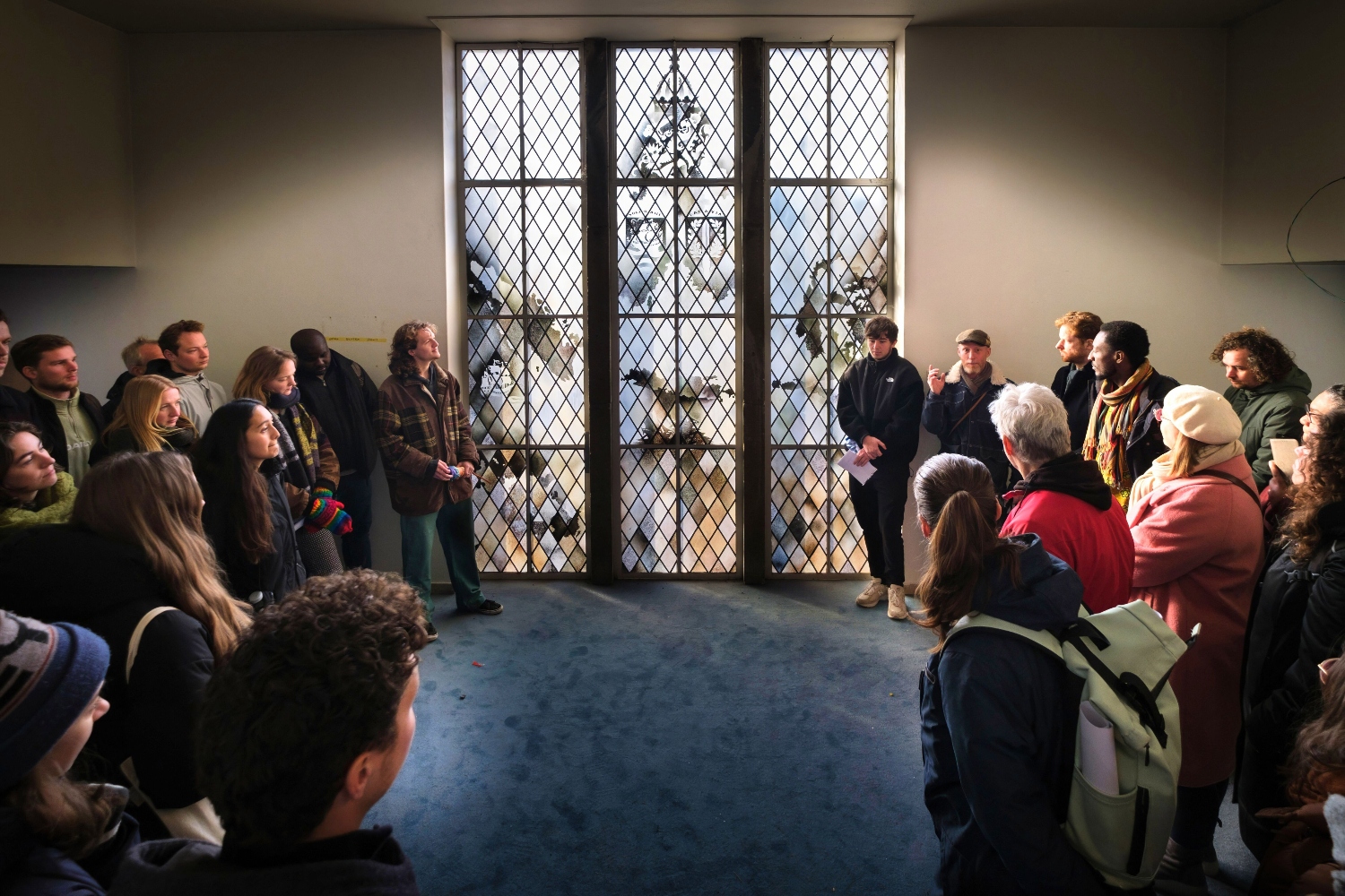 Deelnemers aan de wandeling bekijken het raam van de Wageningse Aula, met bovenin de koloniale aanduidingen 'Batavia' en 'Suriname'.