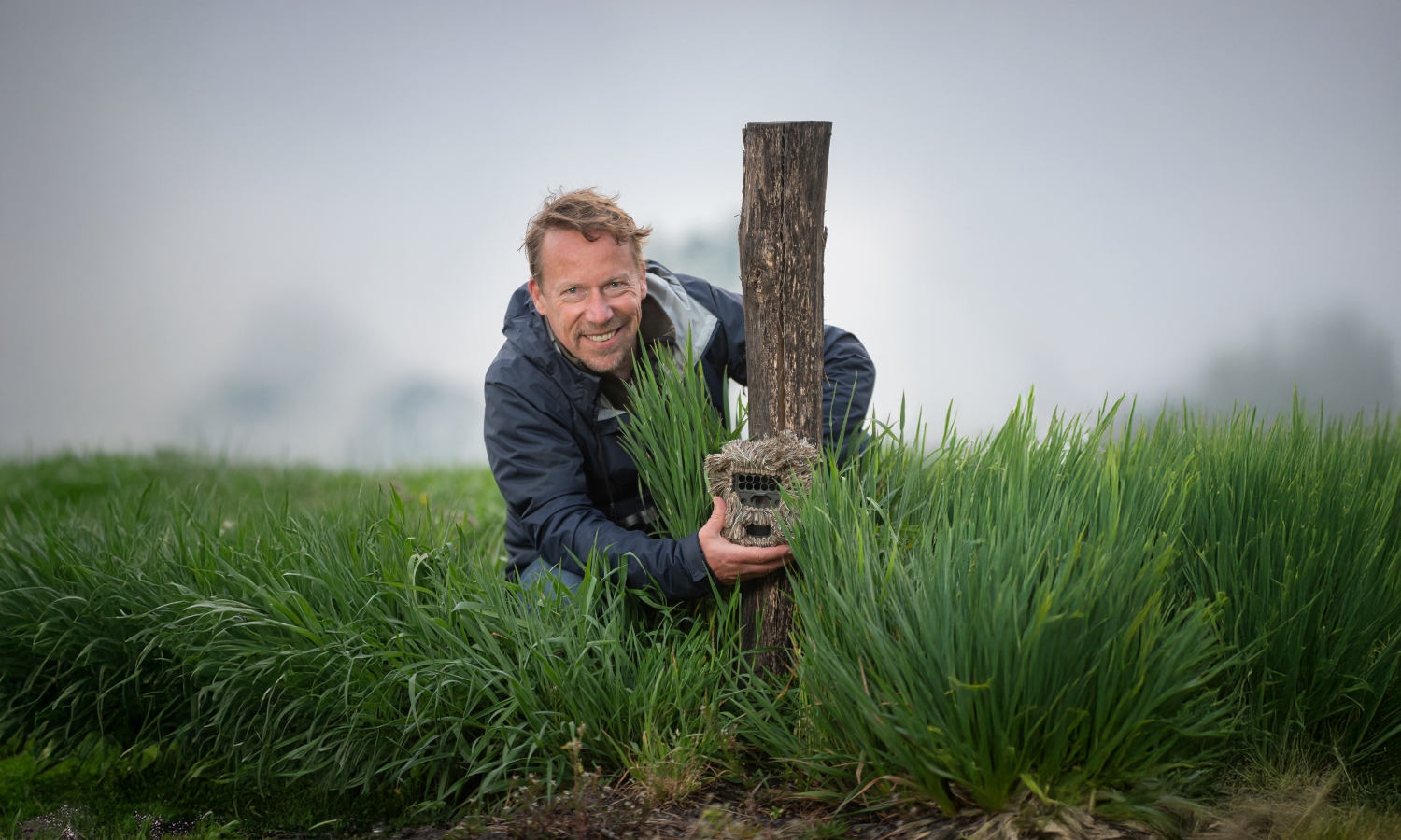 Patrick Jansen gehurkt in het gras bij een cameraval.